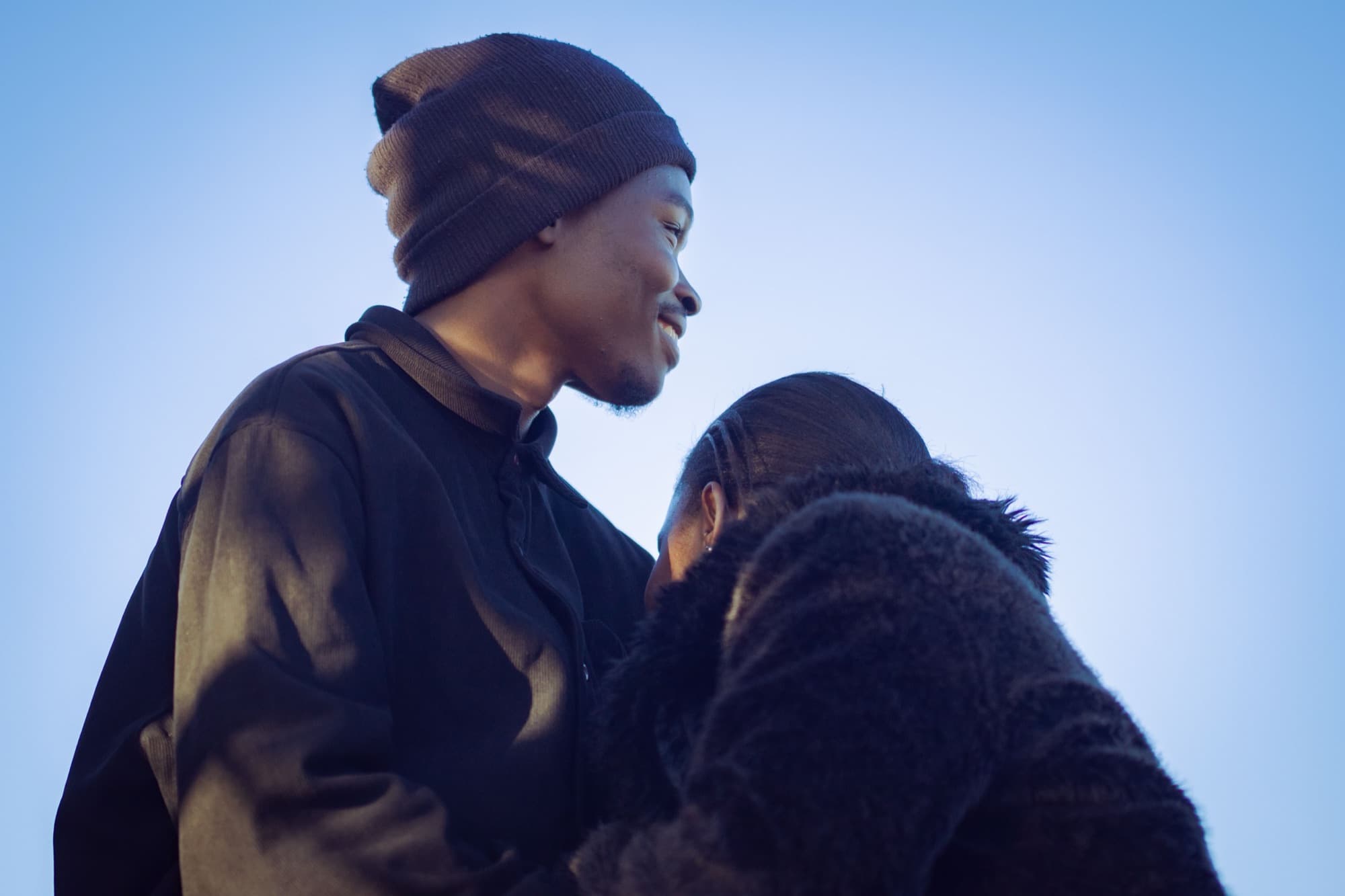 A couple close together outdoors at dusk